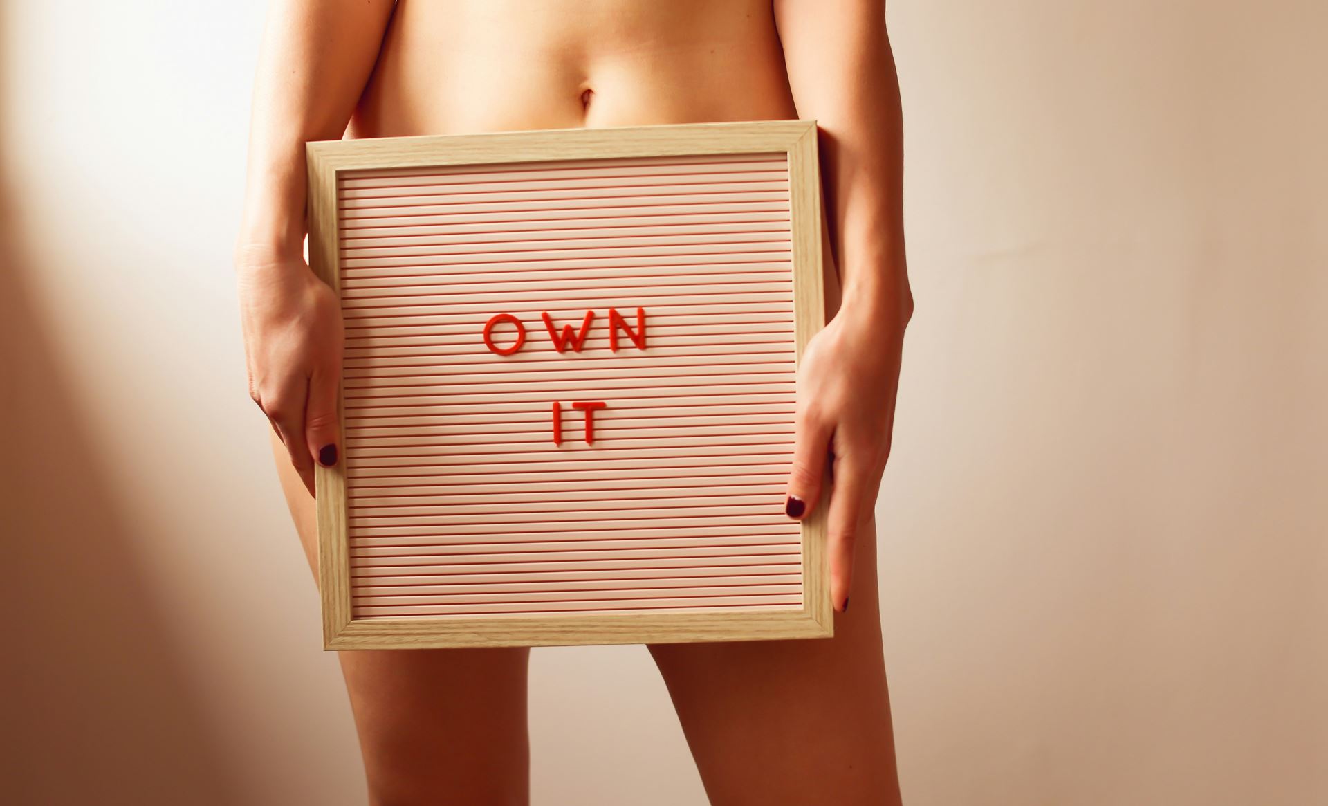 person holding a board saying 'own it' across the lower half of their body